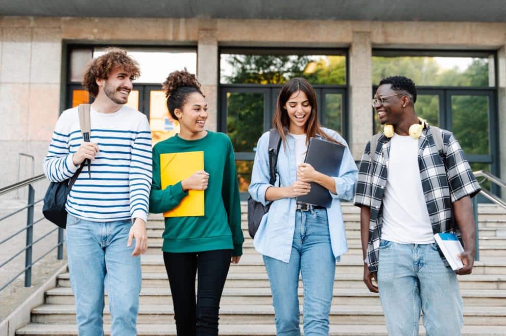 Group of smiling international students walking out of campus building